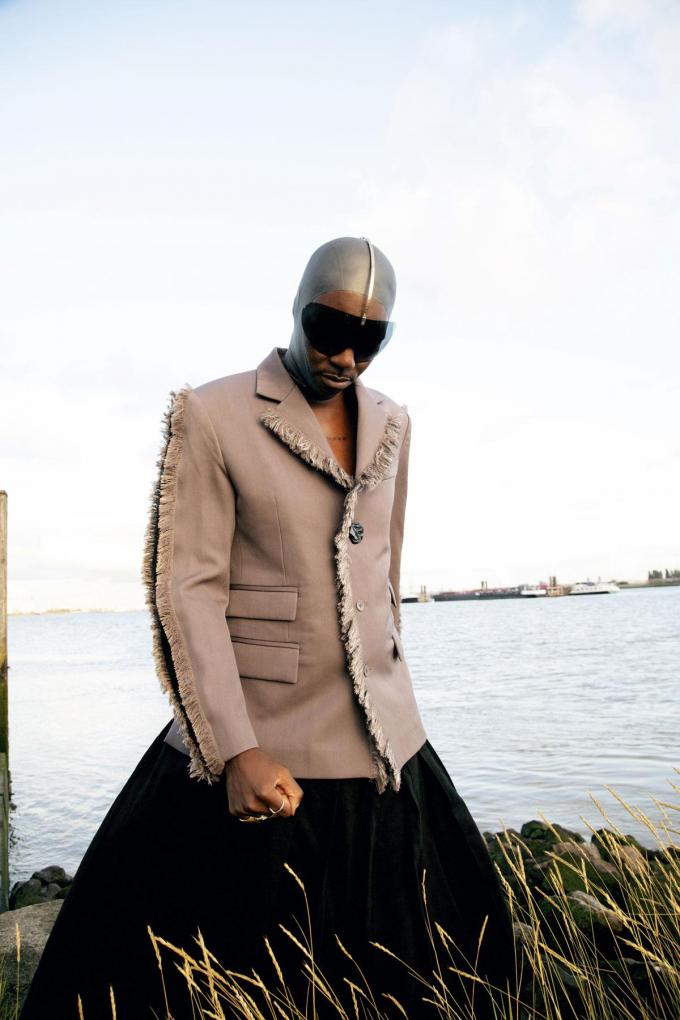Blazer en laine grise avec pantalon assorti, cagoule en latex et masque solaire, Louis Vuitton. Bagues en or personnelles. Bagues en argent, Wouters & Hendrix.