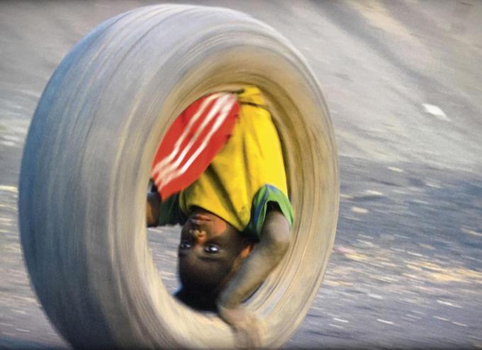 C’est encore Lubumbashi qui est le théâtre de La Roue (2021). Tel un Sisyphe contemporain, un jeune enfant grimpe au sommet d’un terril jouxtant une mine de cobalt. On le suit par moments à l’aide d’une caméra embarquée dans le pneu qui lui sert de véhicule, au fil de sa descente infernale aux allures de métaphore d’un monde en chute libre.