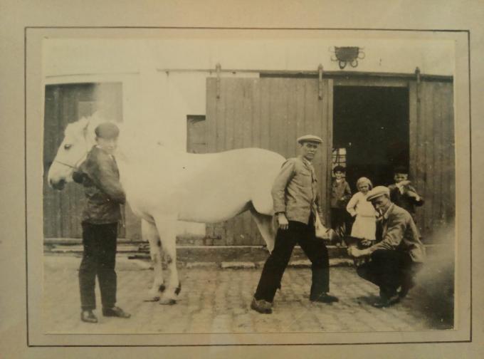 Op de archieffoto van Jerome’s hoefsmederij aan de Blauwe Sluis herken je centraal Jerome Everaert, Charles Everaert heeft het paard vast en Henri Everaert zit neer. Robert Everaert staat uiterst rechts met naast hem zijn zus Martha. De jongen bij de poort is waarschijnlijk een buurjongen.