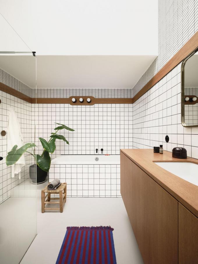 Ook de badkamermeubelen werden op maat gemaakt door Mathieu. Het idee om de witte muren te combineren met hout en zwarte voegen zagen ze op Pinterest.