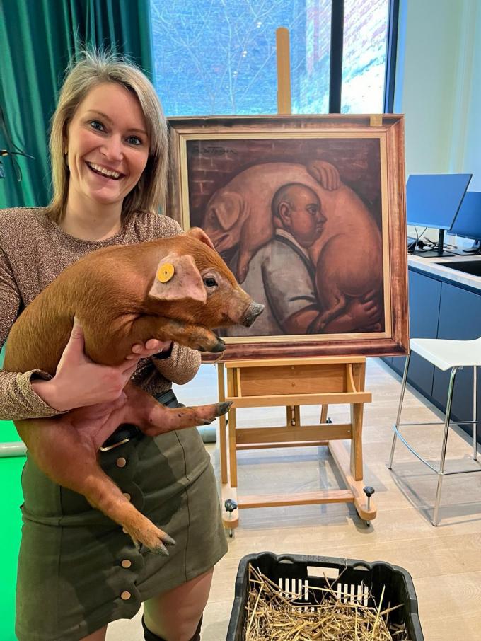 Eline poseert met een biggetje bij het schilderij ‘De varkensboer’ waarover ze vertelt.