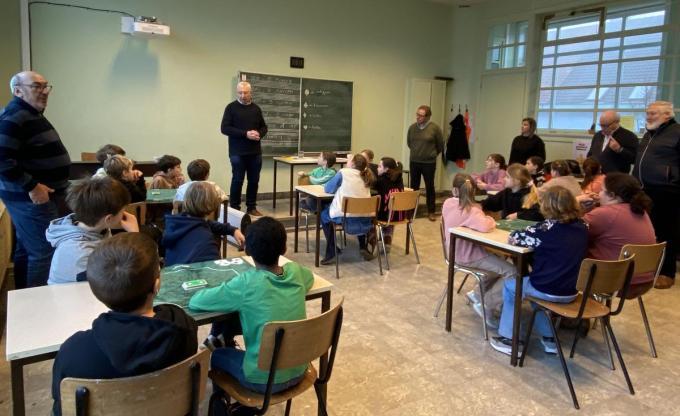 Kinderen van het vierde leerjaar luisteren heel aandachtig hoe ‘leerkracht’ Mark Dewaele uitleg geeft over wat manillen is. De coaches staan klaar om dan per tafel meteen tot de praktijk over te gaan.