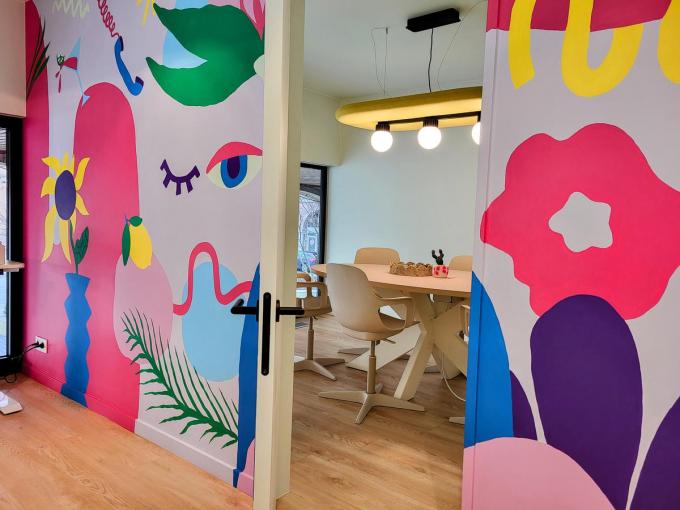 Een kleurrijke muur scheidt de coworkingruimte van de vergaderruimte.