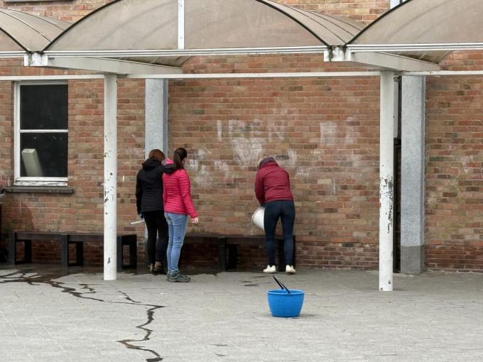 Vrijwilligers spoelen met water alles waar de leerlingen mee in contact kunnen komen.