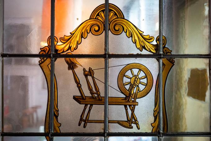 Het glas-in-loodraam aan de ingang, met de afbeelding van een schietspoel, is de enige verwijzing naar het socialistische verleden van het café.