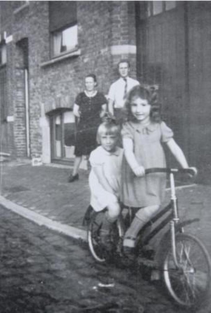 Goldine Ehrenfeld vooraan en Gilberte Janssens achteraan op een kinderfietsje, voor het huis aan de Kolenkaai tijdens WO II.