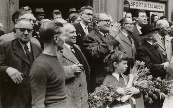 Achiel schouwt de 1-mei stoet voor het Volkshuis in de Steenstraat, achter hem zijn nog piepjonge zoon Frank.