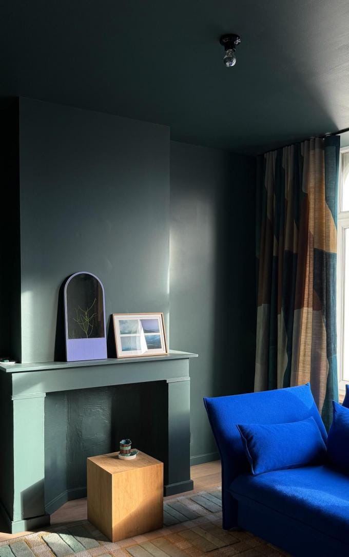 Maximalisme is geen “meer, meer, meer”, het is ritme. In mijn tv-kamer zit dat ritme goed. Donkergroen omsluit de ruimte, het tapijt en de gordijnen doen het duet, en de sofa zorgt voor zachtheid in toon. (foto's Kelly Claessens)