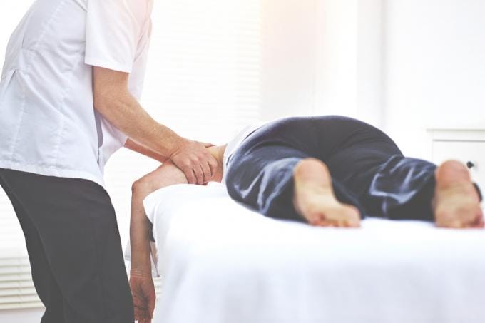 Patiënt wordt behandeld door zorgspecialist en wrijft over linkerarm van patiënt.