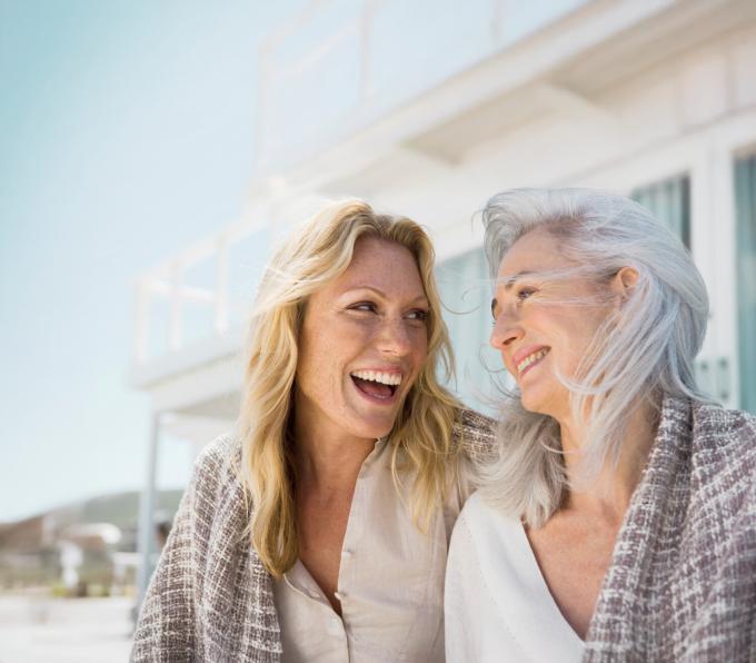 Twee vriendinnen van middelbare leeftijd lachen naar elkaar.