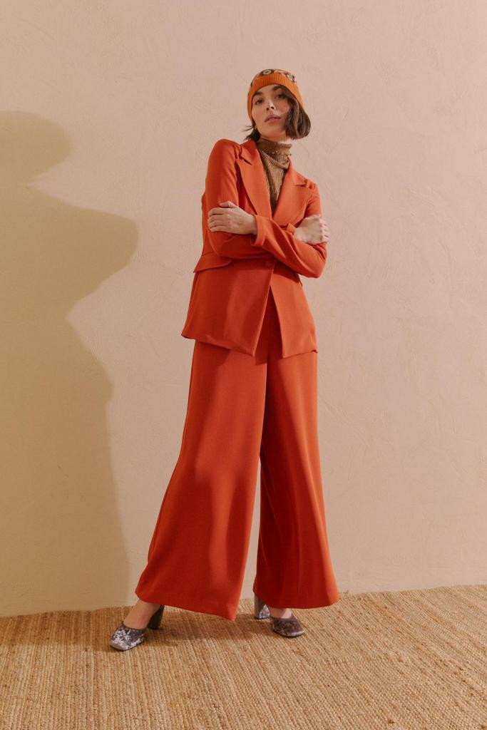 Blazer (318 euro) en wijde broek (210 euro) in een warme herfsttint, fluwelen pumps (365 euro), van Maliparmi.