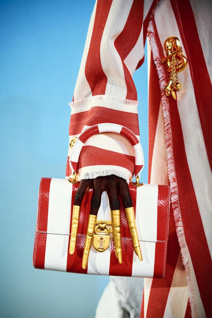Gestreept staat hipHemdjurk met uitgerafelde boord en bijhorende tas in wit-rode strepen, van Schiaparelli (prijs op aanvraag). 