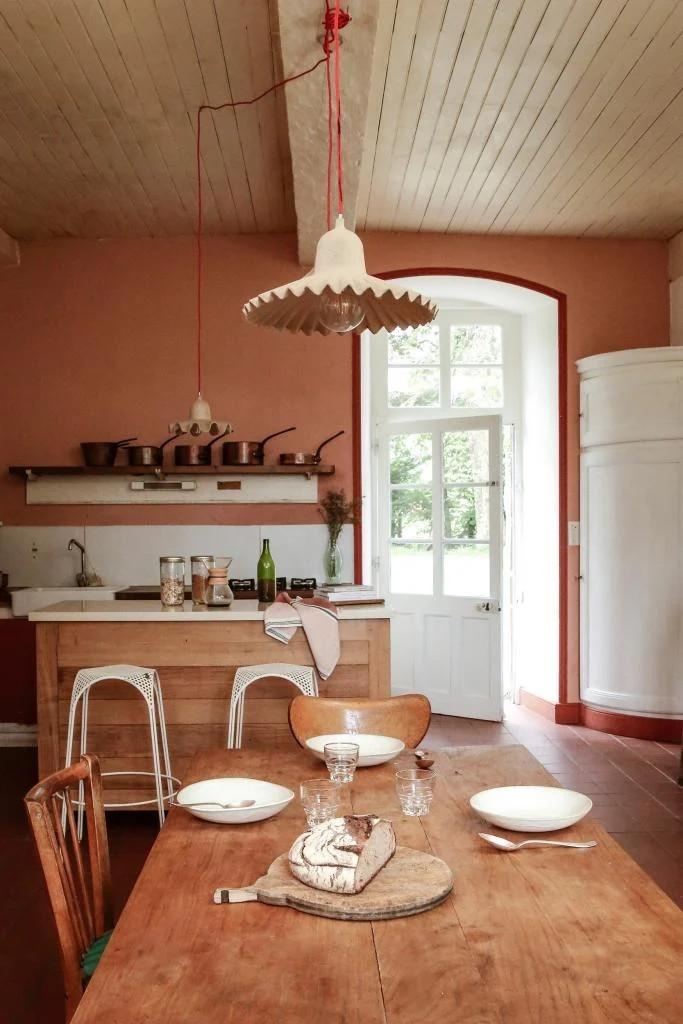 Terracottatinten maken de keuken licht en landelijk. De krukjes zijn vintage Mategot, boven de tafel Egg of Columbus-lampen van Seletti. 