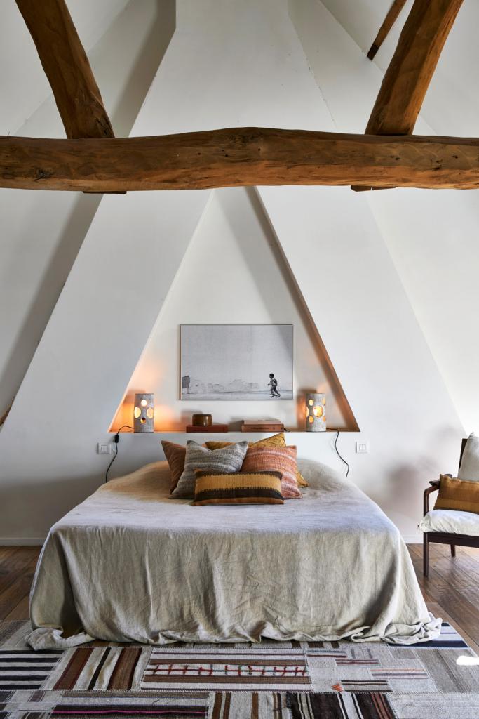 De gezellige slaapkamer onder de nokbalk profiteert van de dubbele hoogte van de bovenverdieping. Ook Bernards schoonzus Geraldine Van Heuverswyn werkte mee aan het interieur.