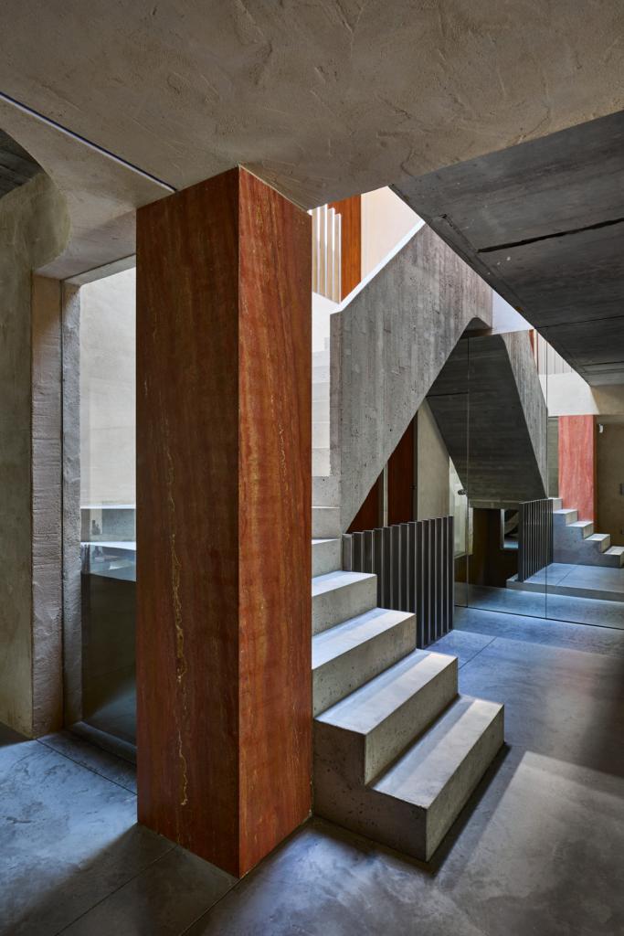 De betonnen structuur rondom de trap werd voorzien van glaspartijen om het effect van een lichtbaken in het hart van de woning te vergroten. Elke wou geen klassieke trapleuning, maar een deconstructivistisch alternatief in de geest van Margiela dat toch genoeg veiligheid voor haar kinderen kon garanderen. Het resultaat? Een ritmische opeenvolging van glimmende inox staven.