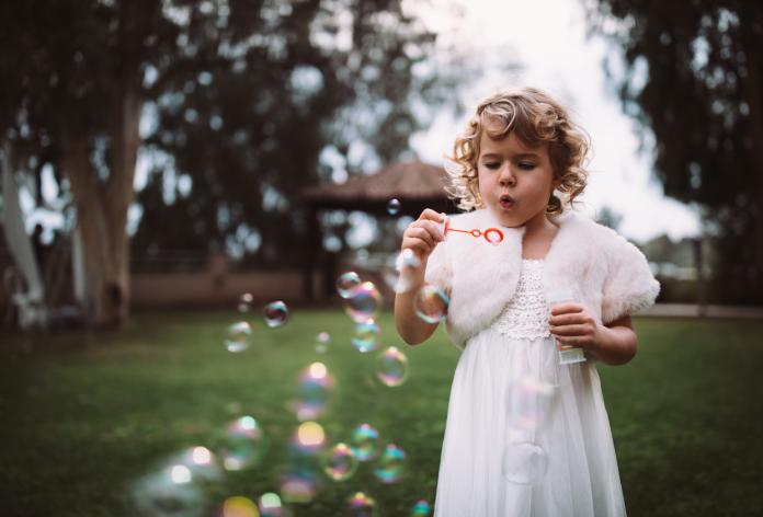 Little flower girl blowing bubbles on wedding day