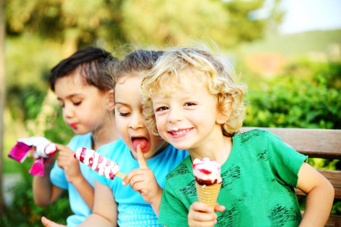 Little girl and boys eating ice cream in the park.