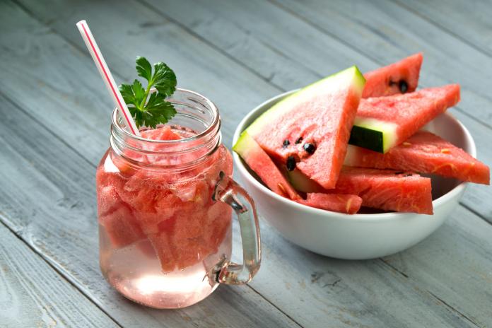 Watermelon smoothie in glass jar and bowl with watermelon slices