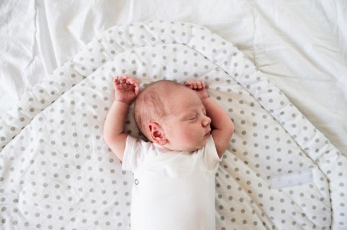 baby slaapt met armen omhoog