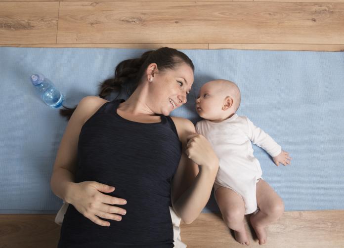 Beautiful young woman exercising with her baby boy