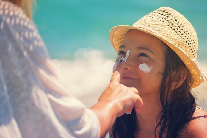 Young Mother Applying Suntan Lotion On Daughter's Face