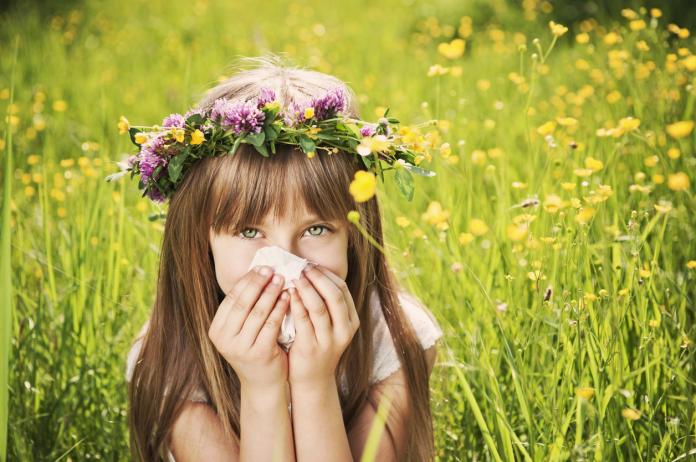 Little girl in grass cleaning her nose