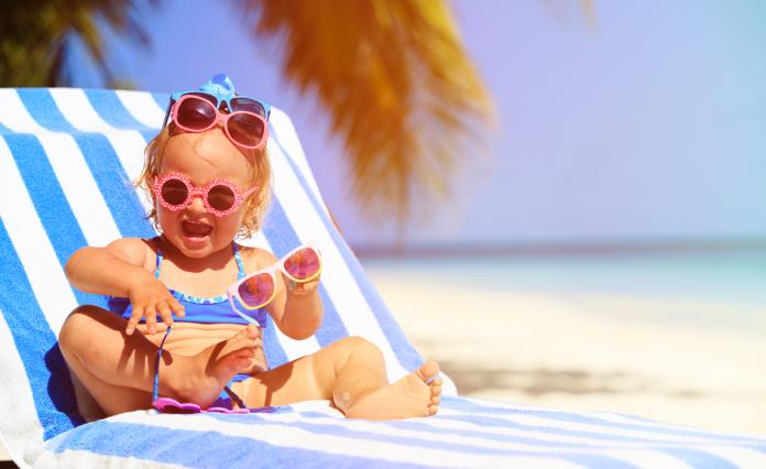 cute little girl trying on sunglasses at beach