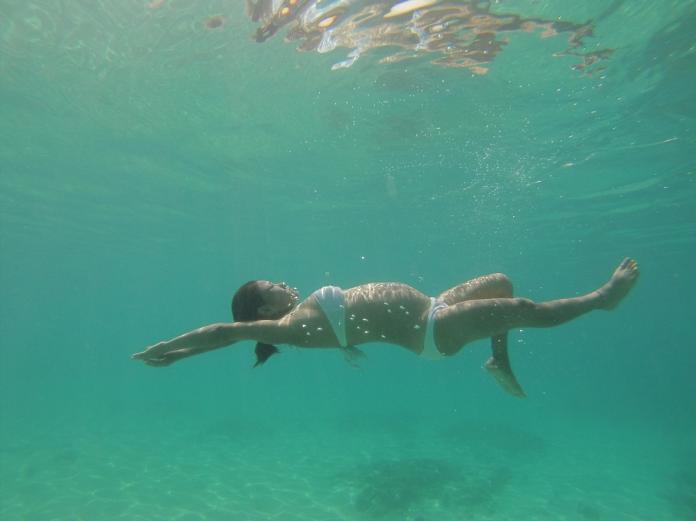 Pregnant Asian woman swimming in ocean