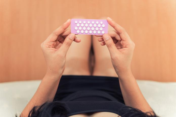 Asian woman holding contraceptive pills in the bed room, Health and medical concept