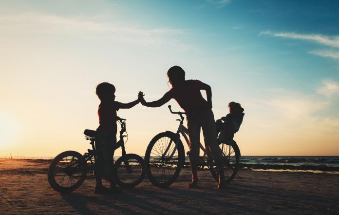 happy mother with kids biking at sunset