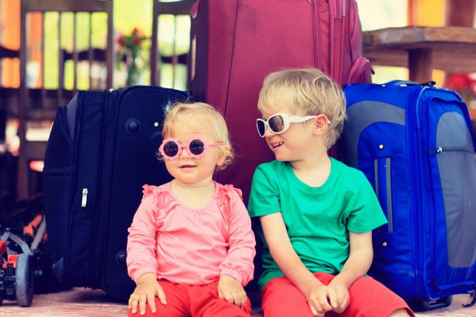 kids sitting on suitcases ready to travel