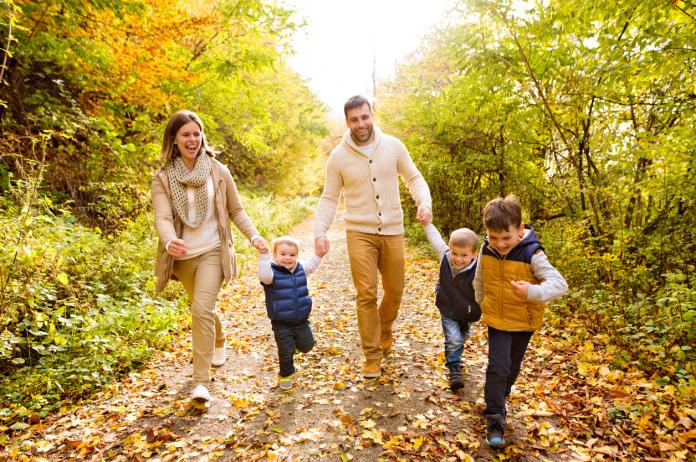Beautiful young family on a walk in autumn forest.