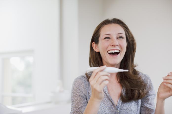 Happy woman holding pregnancy test