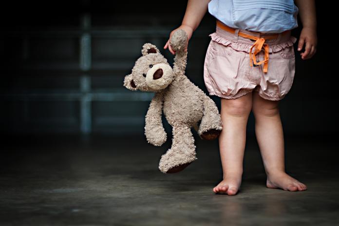 Low section of a girl holding her teddy bear
