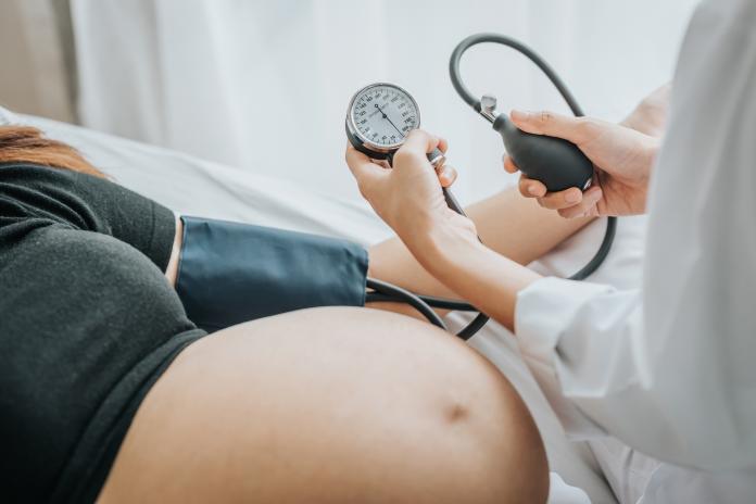 Midsection Of Doctor Examining Pregnant Woman Blood Pressure In Hospital