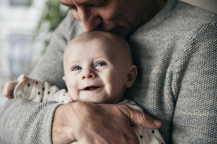Mature father kissing laughing baby on its head