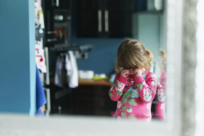 Reflection of upset girl rubbing eyes in mirror