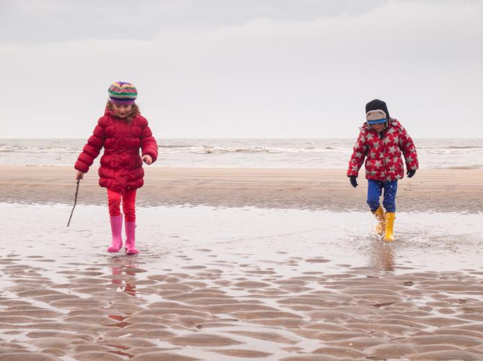 small boy and girl paddling on the beach krokusvakantie aan zee