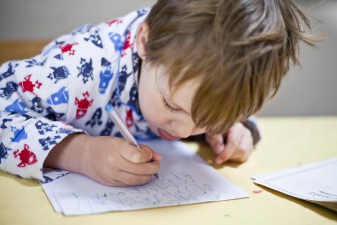 Young boy writing Nationale Pyjamadag