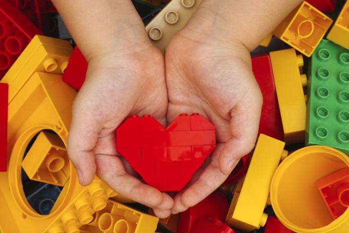 Lego red heart in child hands duplo