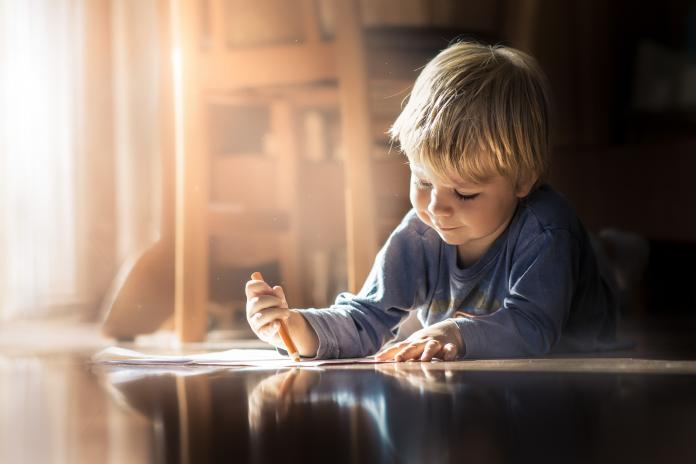 Boy lying on the floor with a coloring book kind met autisme