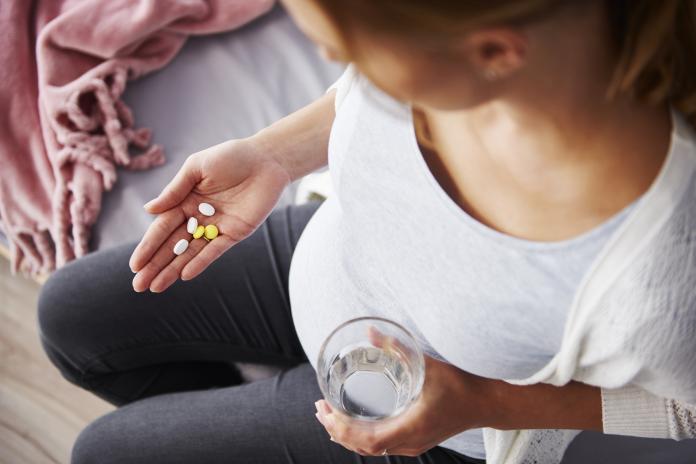 Young pregnant woman taking medicine voedingssupplementen zwangerschap