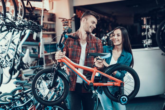 Happy Young Couple Chooses Kids Bicycle in Store kinderfiets kopen