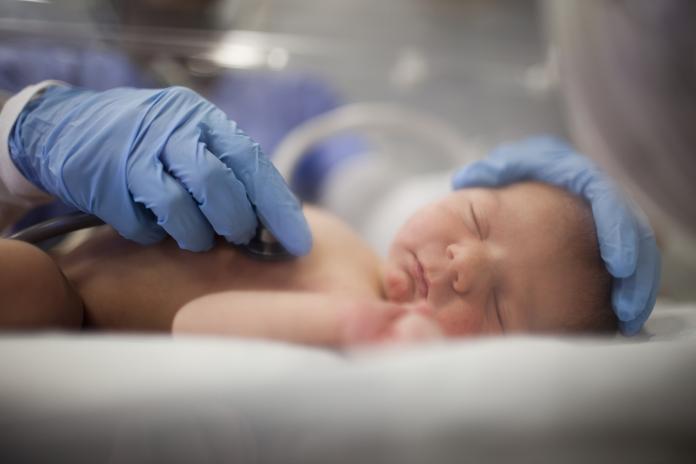 USA, Utah, Payson, Nurse listening to heartbeat of newborn in incubator vroeggeboorte