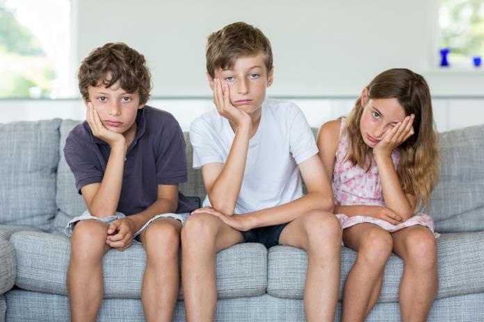 Brothers and sister on sofa looking bored 9 weken zomervakantie overbruggen
