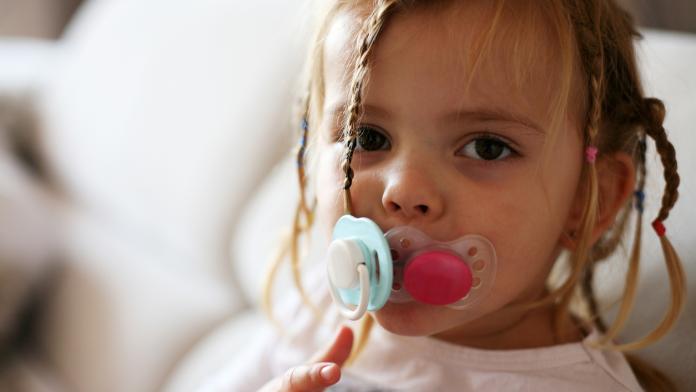 Little girl with two pacifiers.