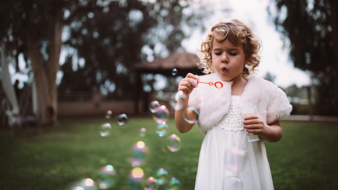 Little flower girl blowing bubbles on wedding day