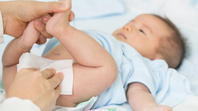 Mother cleaning up and wipes the baby buttocks by wet tissue