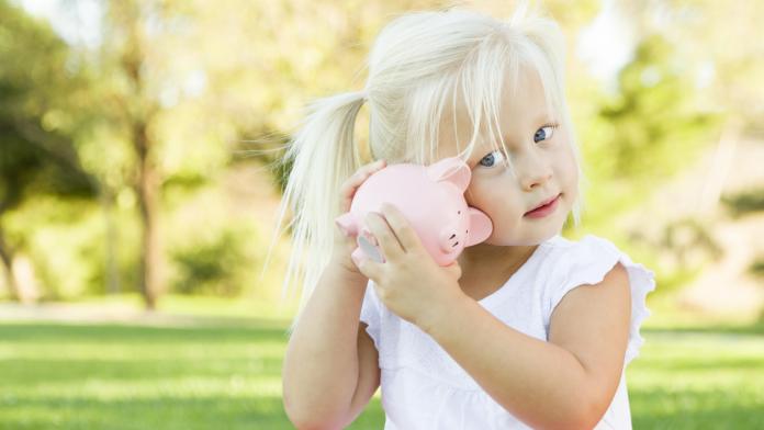 Little Girl Having Fun with Her Piggy Bank Outdoors