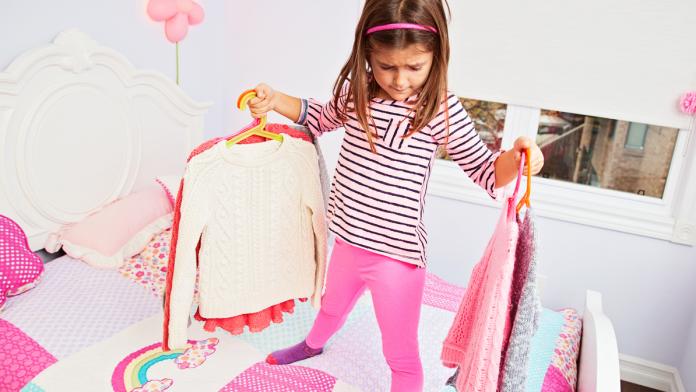 Little girl choosing clothes to wear